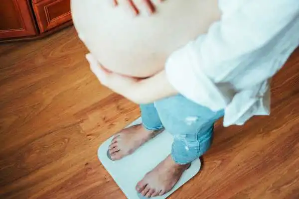 Image of woman weighing herself and experiencing weight gain through pregnancy Avonmouth